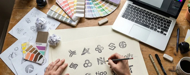 A designer sketching logo marks beside colour swatches